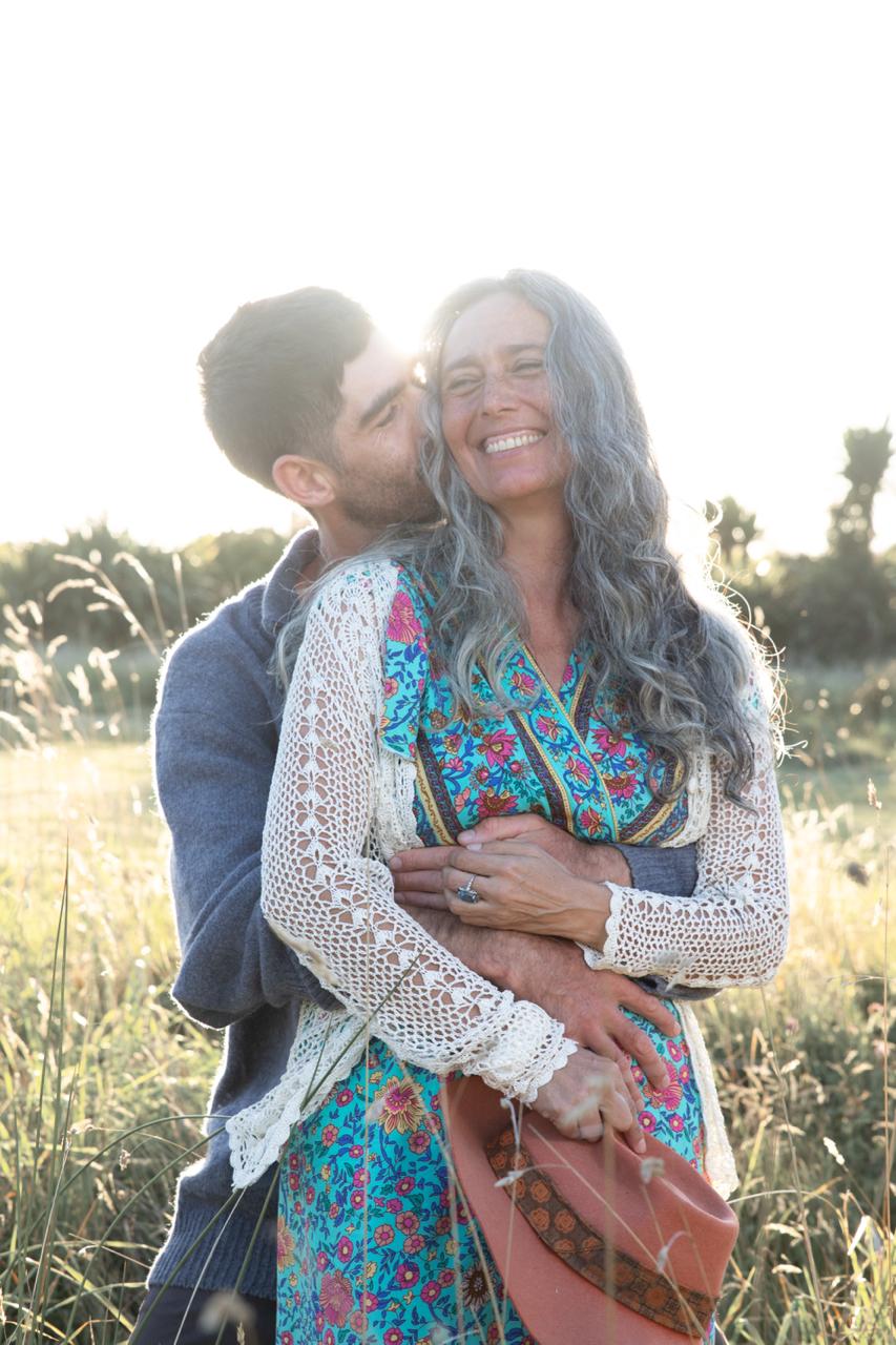 A couple embracing in a sunlit field, the woman smiling